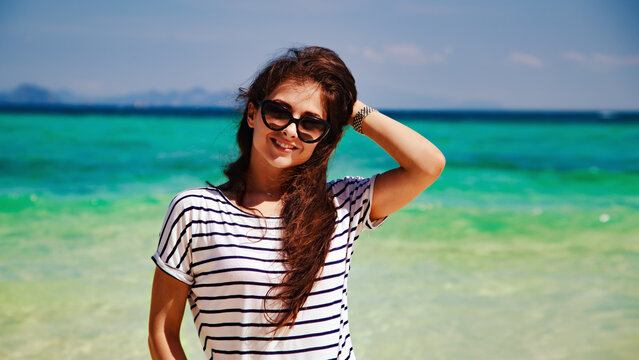 Beautiful happy smiling wonan in fashion sunglasses looking on sunny sea and blue sky background. Closeup rest holidays