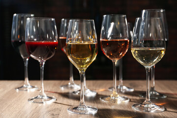 Different tasty wines in glasses on wooden table