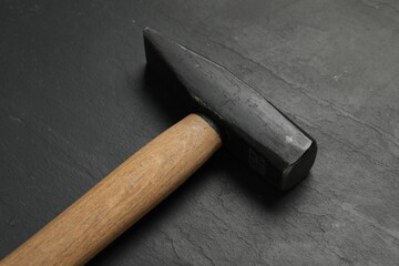 New hammer on black textured table, closeup. Professional construction tool