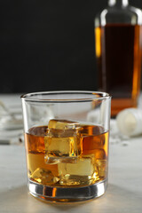 Alcohol addiction. Whiskey with ice cubes in glass on white table