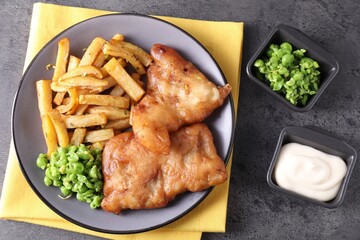 Tasty fish, chips, sauce and peas on grey table, flat lay