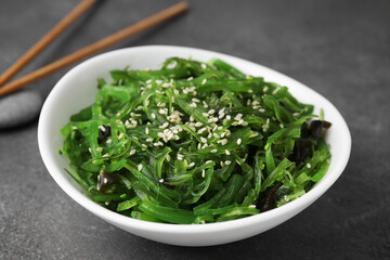 Tasty seaweed salad in bowl served on brown table, closeup