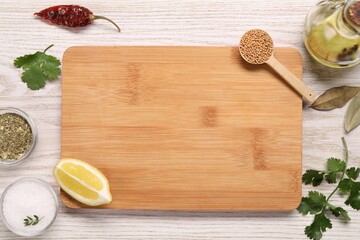 Cutting board, spices, oil and lemon on light wooden table, flat lay. Space for text