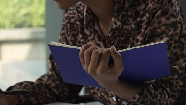 A young African American woman in a blue formal shirt with afro brown hair works as a product designer in a modern office, utilizing skills in design, CAD, CNC, and CNF.