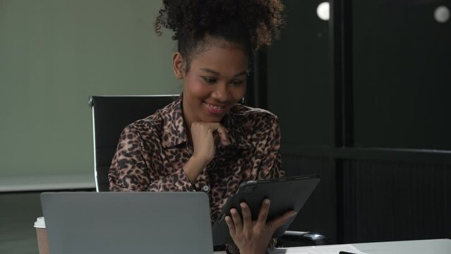 A young African American woman in a blue formal shirt with afro brown hair works as a product designer in a modern office, utilizing skills in design, CAD, CNC, and CNF.