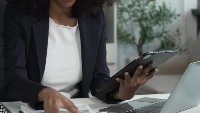 A young African American woman in a blue formal shirt with afro brown hair works as a product designer in a modern office, utilizing skills in design, CAD, CNC, and CNF.