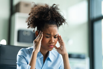 A young African American woman with Afro brown hair in a modern office experiencing panic,...