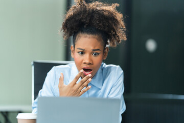 A young African American woman with Afro brown hair in a modern office experiencing panic,...