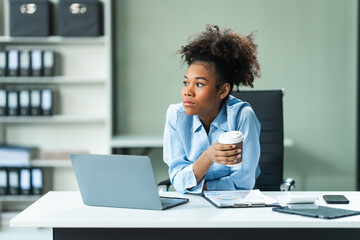 A young African American woman in a blue formal shirt with afro brown hair experiences office...