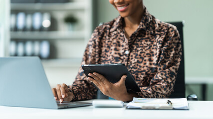 A young African American woman in a blue formal shirt with afro brown hair works as a product...