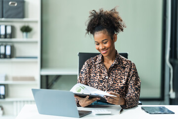 A young African American woman in a blue formal shirt with afro brown hair works as a product...