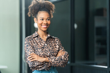 A young African American woman in a blue formal shirt with afro brown hair works as a product...