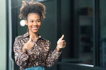 A young African American woman in a blue formal shirt with afro brown hair works as a product...