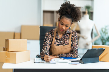 A young African American woman with afro brown hair works in a modern office, managing her small...