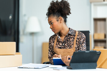 A young African American woman with afro brown hair works in a modern office, managing her small...