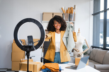 A young African American woman with afro brown hair works in a modern office, managing her online...