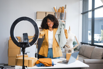 A young African American woman with afro brown hair works in a modern office, managing her online...