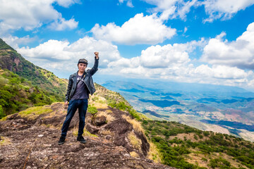 Man with his arm raised on the top of a mountain in Nanchititla state of Mexico 