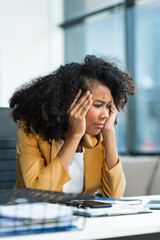 A young African American woman with Afro brown hair in a modern office experiencing panic,...