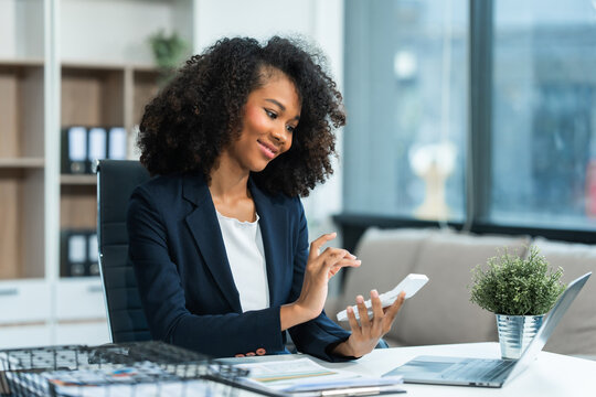A young African American woman in a blue formal shirt with afro brown hair works as a product designer in a modern office, utilizing skills in design, CAD, CNC, and CNF.