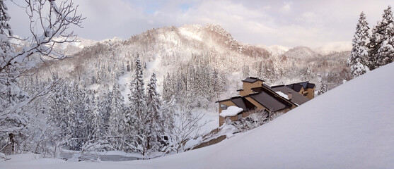 Beautiful Japanese satoyama winter scenery, with forest on the hill covered with deep snow,...