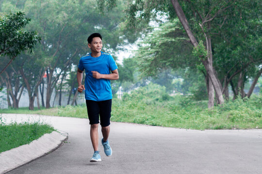 Asian Man Running in Light Blue Sports Outfit in the morning