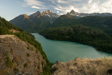 Grass Covered Cliffs Make A Steep Drop Down to Diablo Lake Below And The North Cascades In The Distance