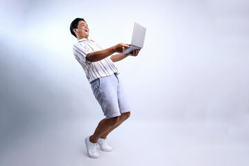 Full Length Of Attractive Asian Man Suprised Looking At Laptop Isolated On White Background