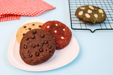 Various Homemade Cookies Arrange on Plate and Cooling Rack Isolated on Blue Background