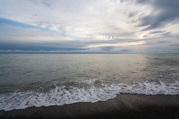 An incoming wave on the Black Sea coast against the sunset sky, Sochi, Krasnodar Territory, Russia