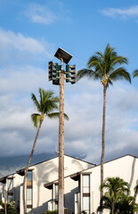 Topical setting with solar powered tsunami sirens in front of apartment building and palm trees,...