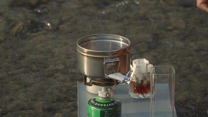 The Bushcraft concept makes pandan cream coffee in a clear river upstream with ASMR sounds. Close up of cooking activities in nature with minimal equipment in a calm and comfortable atmosphere