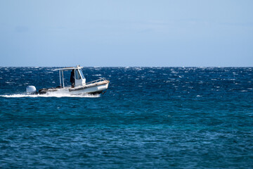 Small motor boat cruising on a calm pacific ocean on a sunny day, water, sky, and horizon, Maui, Hawaii
