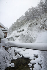 Beautiful Japanese winter scenery, small village with traditional houses, bridges and big snowdrifts, river, pine forest in snow on the hill, Ginzan onsen, nature of Yamagata, Japan