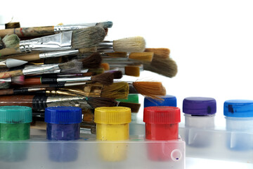 Cans of acrylic paint alongside array of paintbrushes