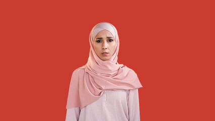 Scared woman. Fear anxiety. Stress problem. Disturbed shocked frightened female face in hijab with open mouth isolated on red copy space background.