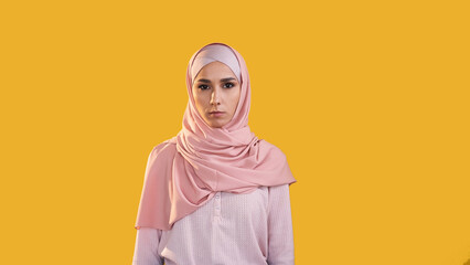 Muslim woman. Modest beauty. Portrait of confident religious girl in islamic hijab headscarf isolated on yellow empty space advertising background.