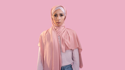 Scared woman. Fear anxiety. Female rights. Disturbed overwhelmed girl face in hijab muslim headscarf isolated on pink empty space background.