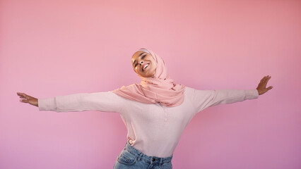 Female freedom. Positive lifestyle. Joy energy. Amused relaxed carefree woman in headscarf dancing isolated on pink copy space background.
