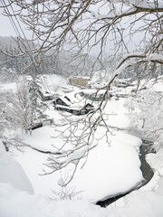 Beautiful Japanese winter scenery, small village with traditional houses,  mountain river, pine forest in snow on the hill, Ginzan onsen hot spring, nature of Yamagata, Japan