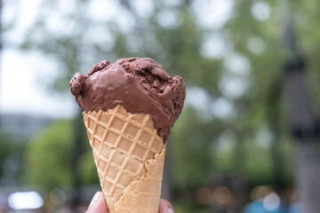 A male hand holding an ice cream chocolate in waffle cone. Vacation and fun, relax and enjoy