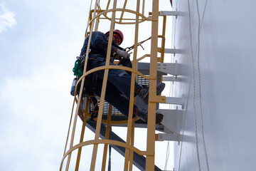 Tester man rested as he climbed a ladder to the roof of the storage tank to sprinkle it with rope.