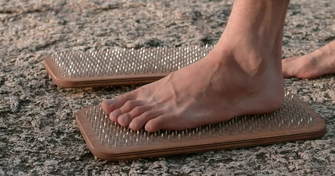 Feet standing on sadhu boards with nails close-up Sadhu boards test of mental fortitude. Sadhu boards acupuncture promoting wellness Practice rooted in tradition symbolizing resilience human spirit.