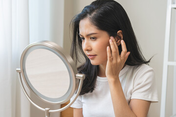 Anti aging beauty, happy asian young woman looking in mirror reflection at home, touching face skin...