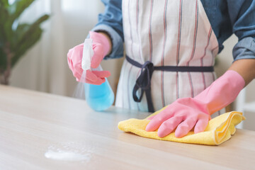 Cleanliness asian young woman working chore cleaning on table at home, hand wearing glove using rag...