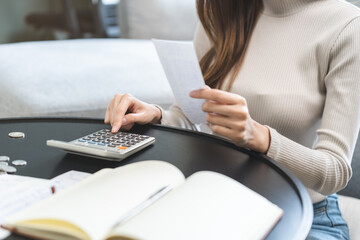 Stressed asian young business woman, employee using calculator to calculate expenses of monthly,...