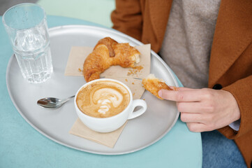 Close-up of a woman eating a croissant during breakfast