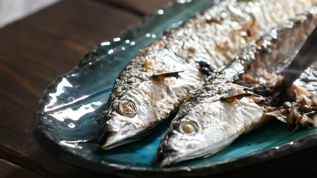 秋の味覚の秋刀魚。焼きたての焼き魚、サンマを食べる動画。クローズアップ。