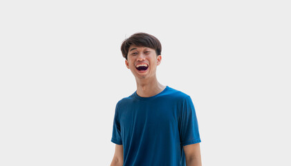 Young Asian man in blue t-shirt making funny face isolated on gray background.