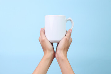 Hands Holding White Ceramic Mug for Mockup Isolated on Blue Background